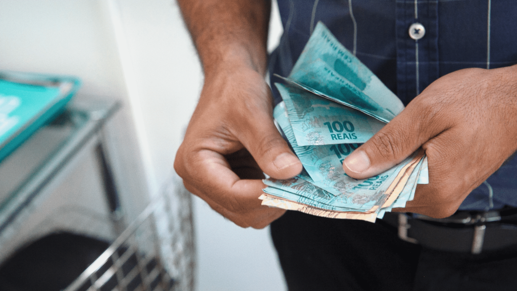 Homem com maço de dinheiro nas mãos - Contabiehl
